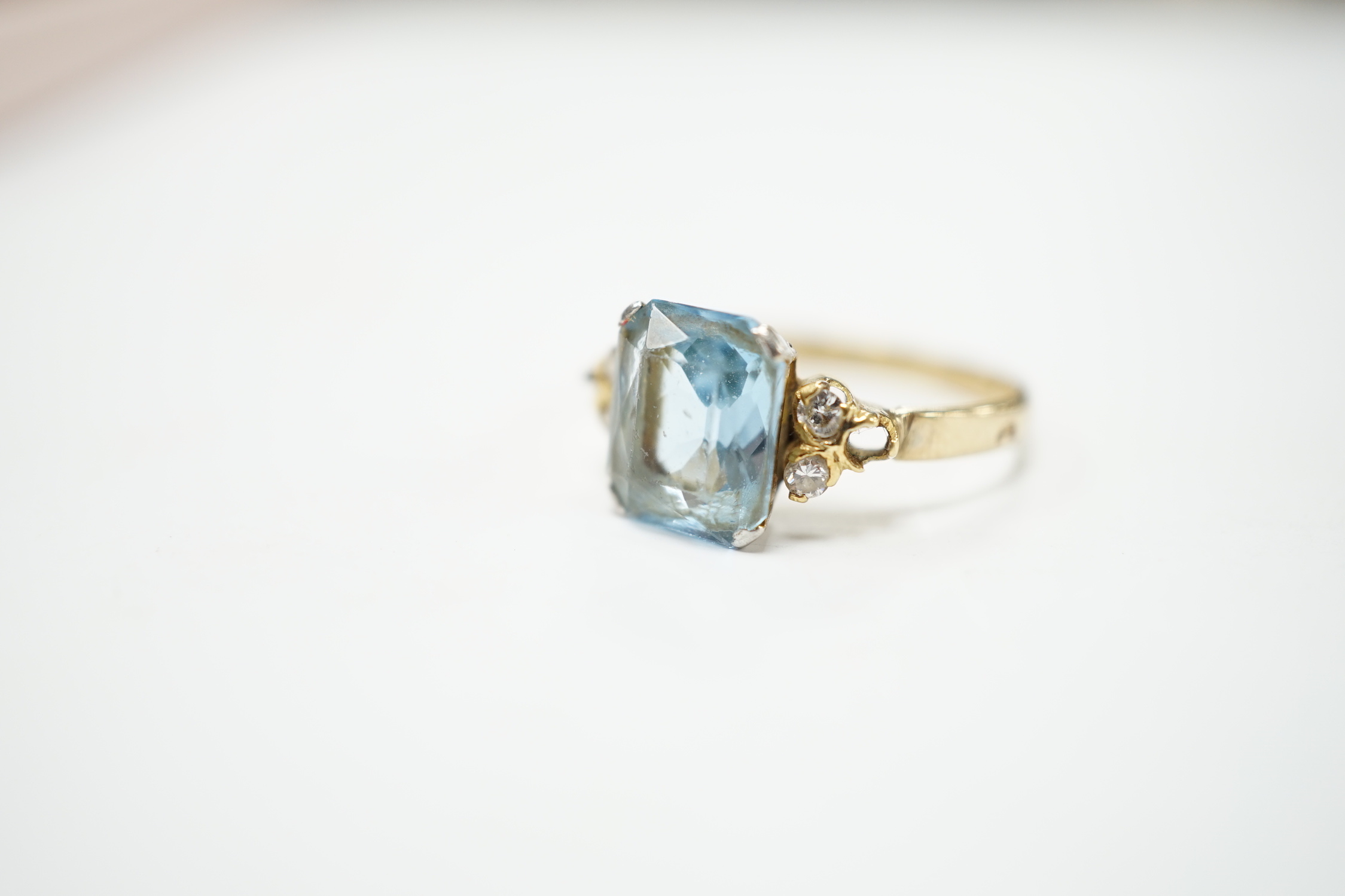 A yellow metal, single stone aquamarine and four stone diamond chip set dress ring, size M, gross weight 2.2 grams.